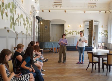 Fotografia grupy ludzi w zabytkowym wnętrzu na próbie teatralnej