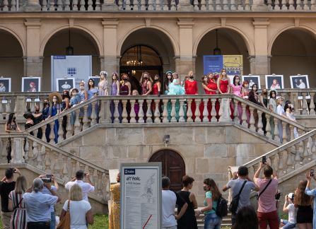 Fotografia. Kobiety w kolorowych sukniach pozują do zdjęcia na schodach przed Willą Decjusza.