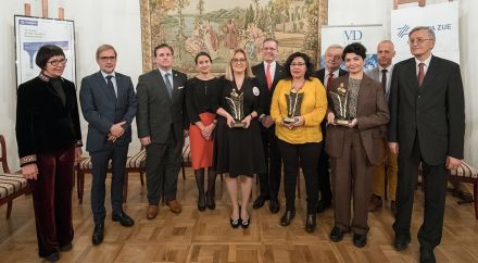 Fotografia grupy elegancko ubranych ludzi na tle gobelinu