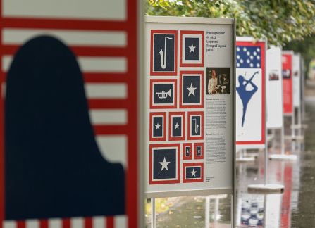 A photograph. An opening of the outdoor exhibition titled Polish Americans, American poles at planty in Krakow. posters standing in a row.