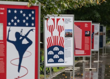 Fotografia. Otwarcie wystawy plenerowej pod tytułem polscy Amerykanie, amerykańscy Polacy na krakowskich plantach. plakaty ustawione w rzędzie.
