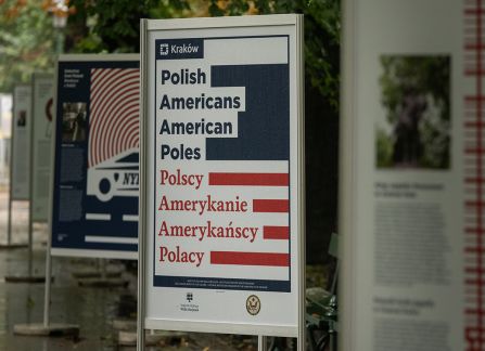 A photograph. An opening of the outdoor exhibition titled Polish Americans, American poles at planty in Krakow. posters standing in a row.