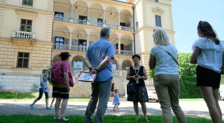 Fotografia grupy zwiedzających z przewodniczką na tle Willi Decjusza