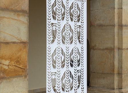 fotografia. wielkoformatowa wycinanka z tradycyjnym wzorem, eksponowana pomiędzy kolumnami arkad na fasadzie willi decjusza.